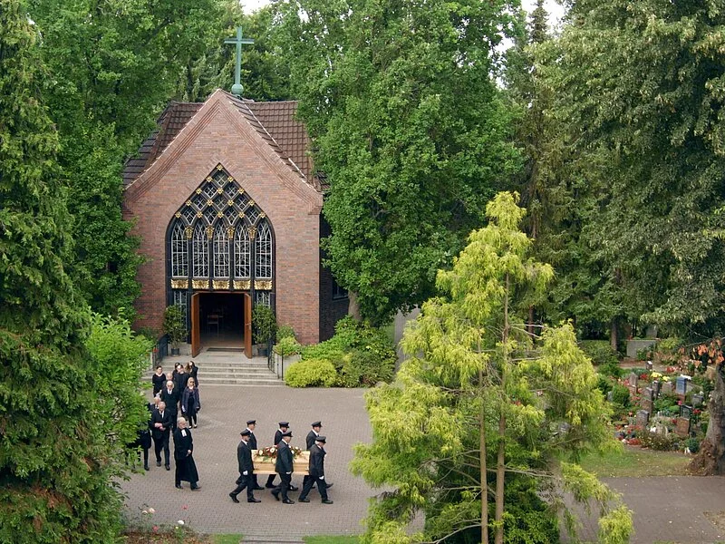 Friedhofskapelle vor der ein kleiner Trauermarsch stattfindet.