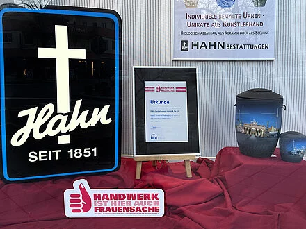 Urkunde für Hahn von "Handwerk ist Frauensache", daneben eine Urne und das Logo von Hahn.