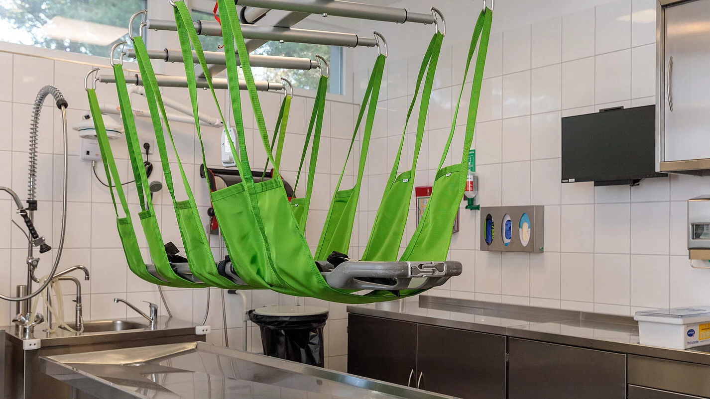 An Seilen befestigte Einbalsamierungsliege über einem Metalltisch.