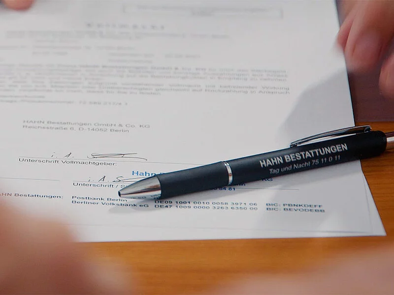 Unterschrift unter einem Vertrag mit hingelegtem Stift.