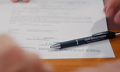 Unterschrift unter einem Vertrag mit hingelegtem Stift.