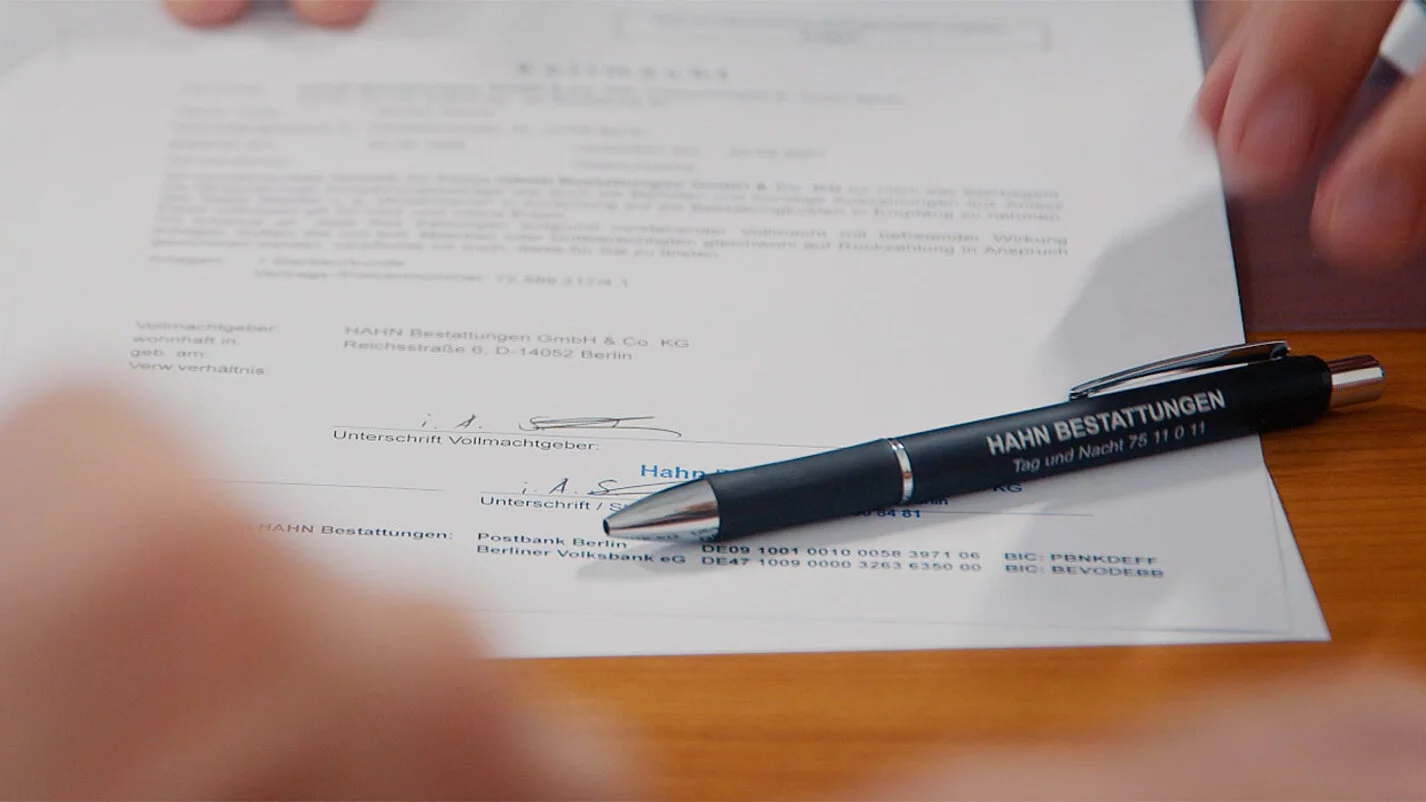 Unterschrift unter einem Vertrag mit hingelegtem Stift.