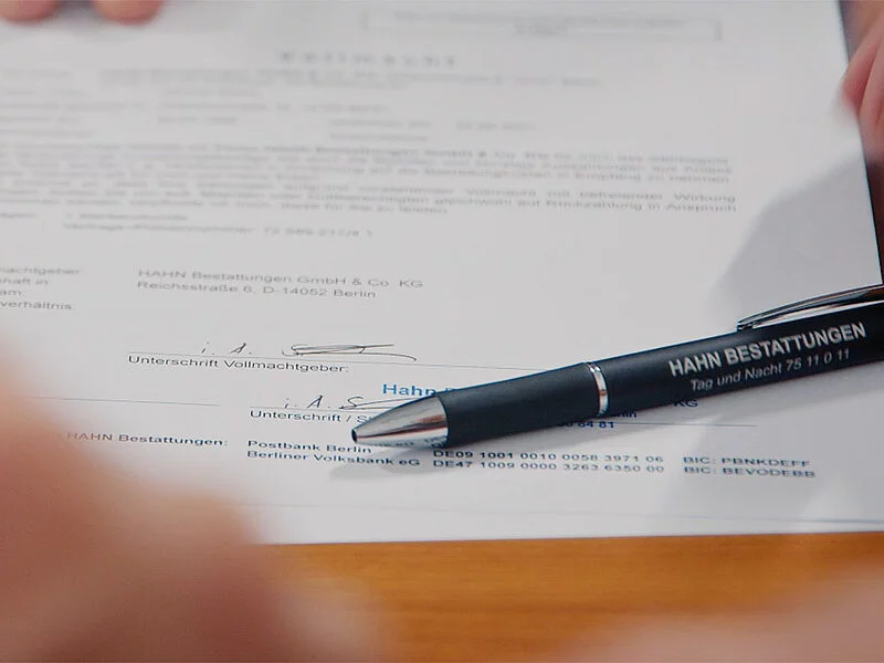 Unterschrift unter einem Vertrag mit hingelegtem Stift.