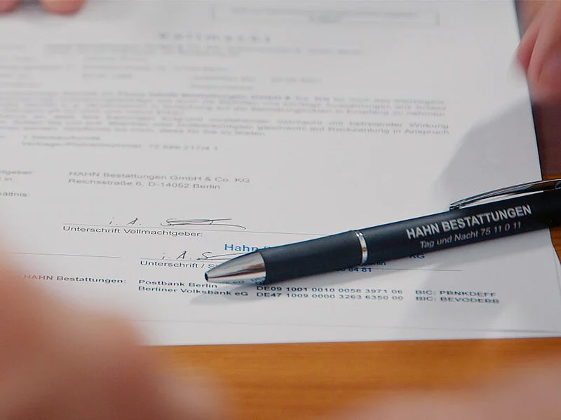 Unterschrift unter einem Vertrag mit hingelegtem Stift.